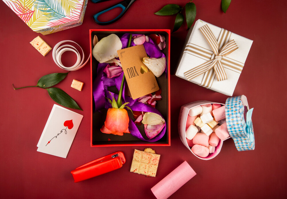 top-view-red-present-box-with-brown-paper-card-coral-color-rose-flower-petals-with-purple-ribbon-heart-shaped-box-filled-with-marshmallow-dark-red-table (1) מתנות לראש השנה לעובדים מאמר